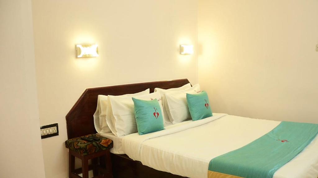 a bedroom with a bed with blue and white pillows at Hotel Mount View in Kodaikānāl