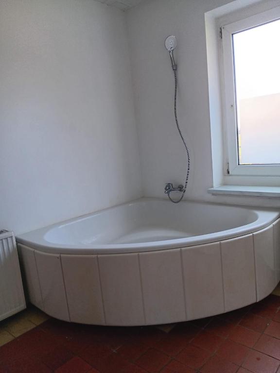 eine weiße Badewanne in einem Zimmer mit Fenster in der Unterkunft Charmant 90 E in Lichterfelde