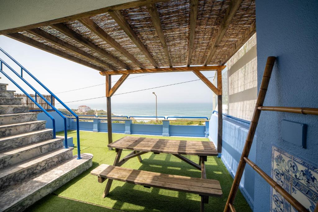 a picnic table on a balcony with a view of the ocean at Saltline Surf House Ericeira in Ericeira