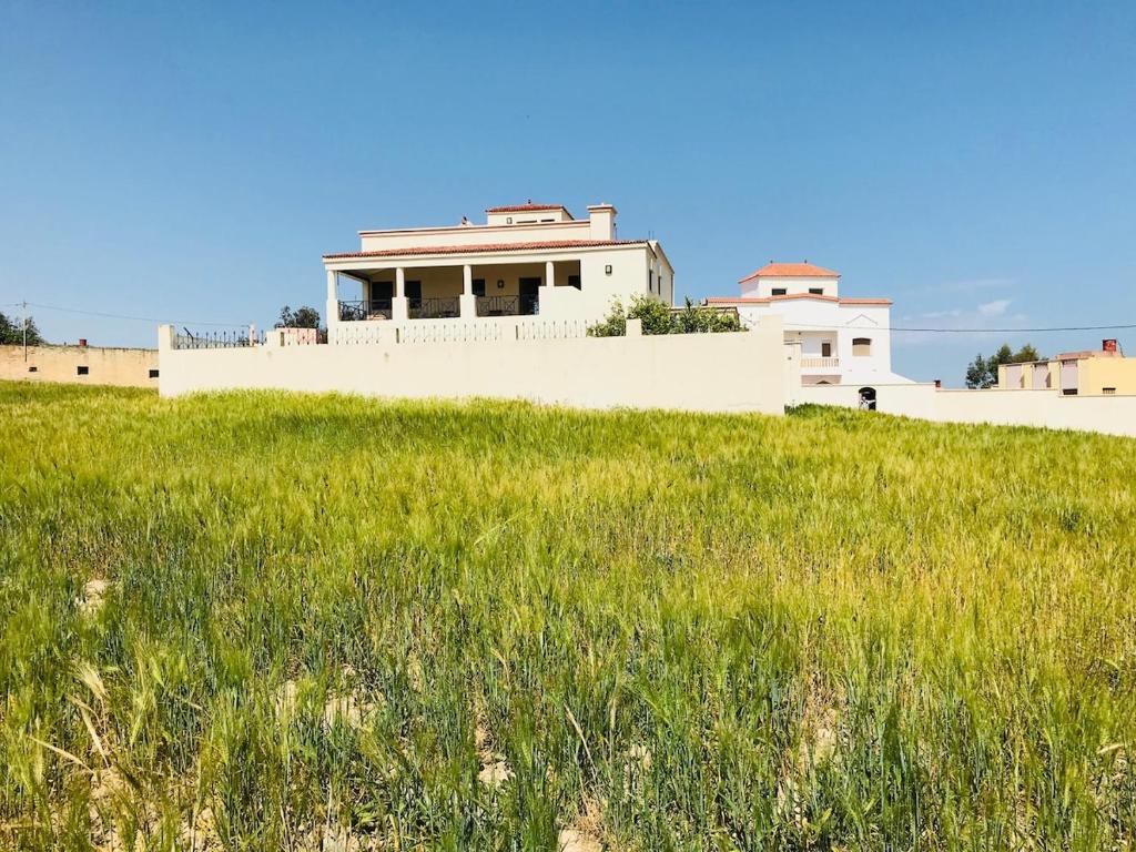 a house on top of a hill with a field of grass at Villa Adan in Sidi Salah