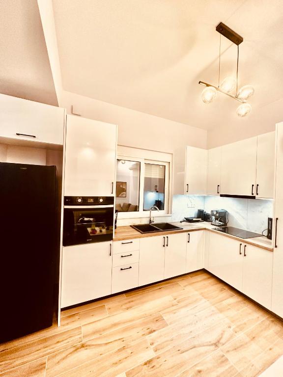 a kitchen with white cabinets and a black refrigerator at Almyrolithos in Gythio