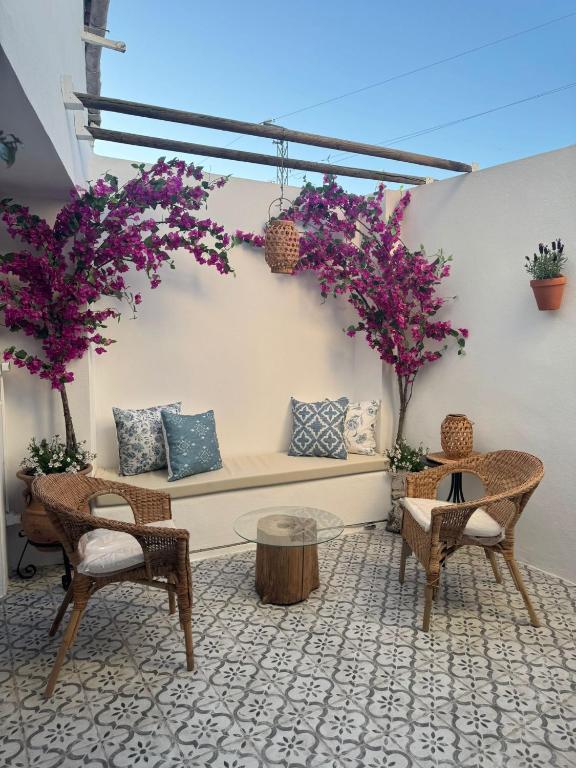 a patio with two chairs and a bench with purple flowers at Casa Rural Hortensia in Zuheros