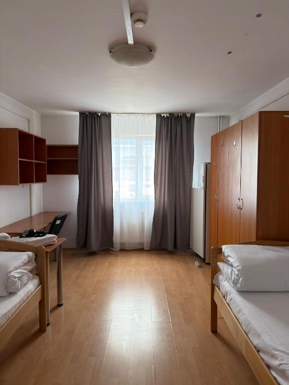 a room with two beds and a table and a window at ZipStay Inn in Cluj-Napoca