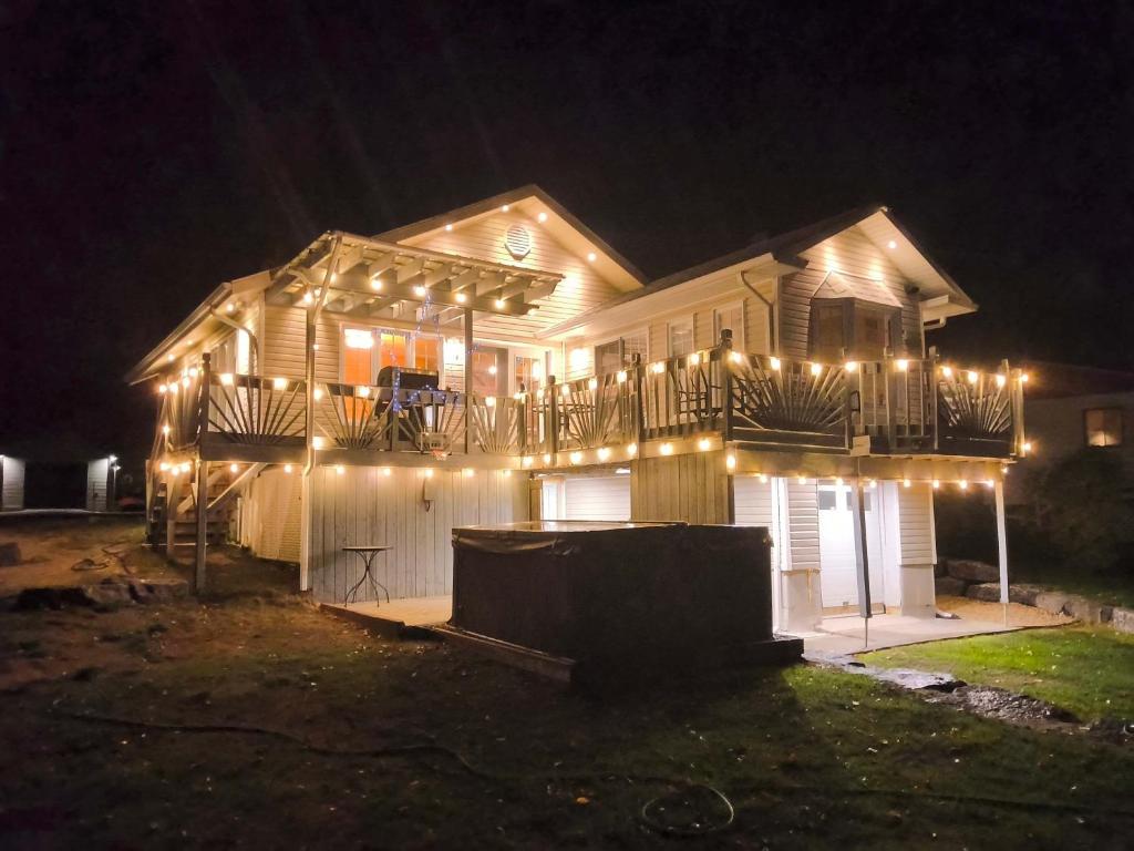a house with a deck with lights on it at night at Waterfront with Spa - Etoile Filante in Saint Zenon