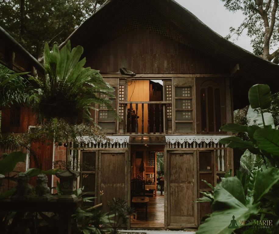 a house with wooden doors and a fence at Zen Marie Tanay in Sampong