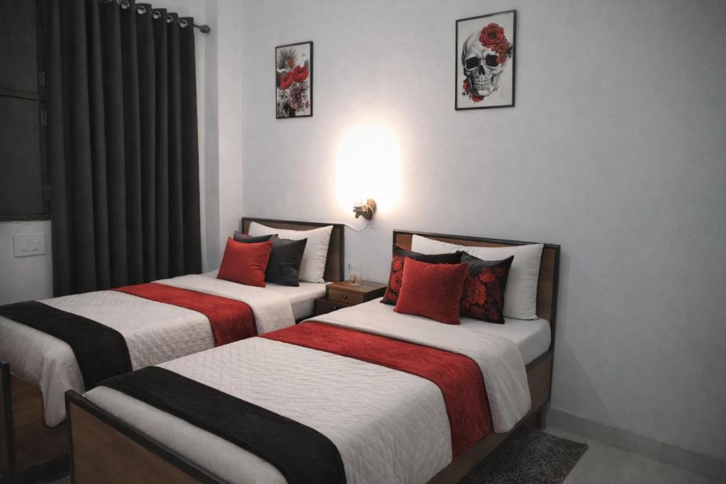 two beds in a hotel room with red and white at La vie Livings Only For Female in Noida