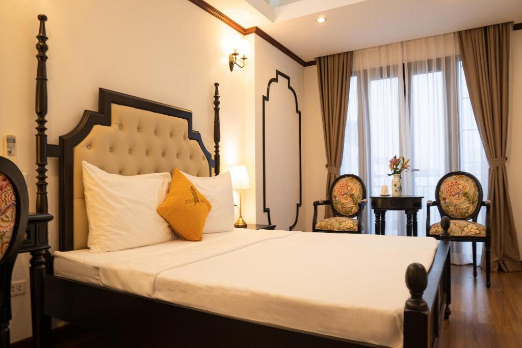 a bedroom with a large bed with two chairs at Maison Julie Duong in Hanoi