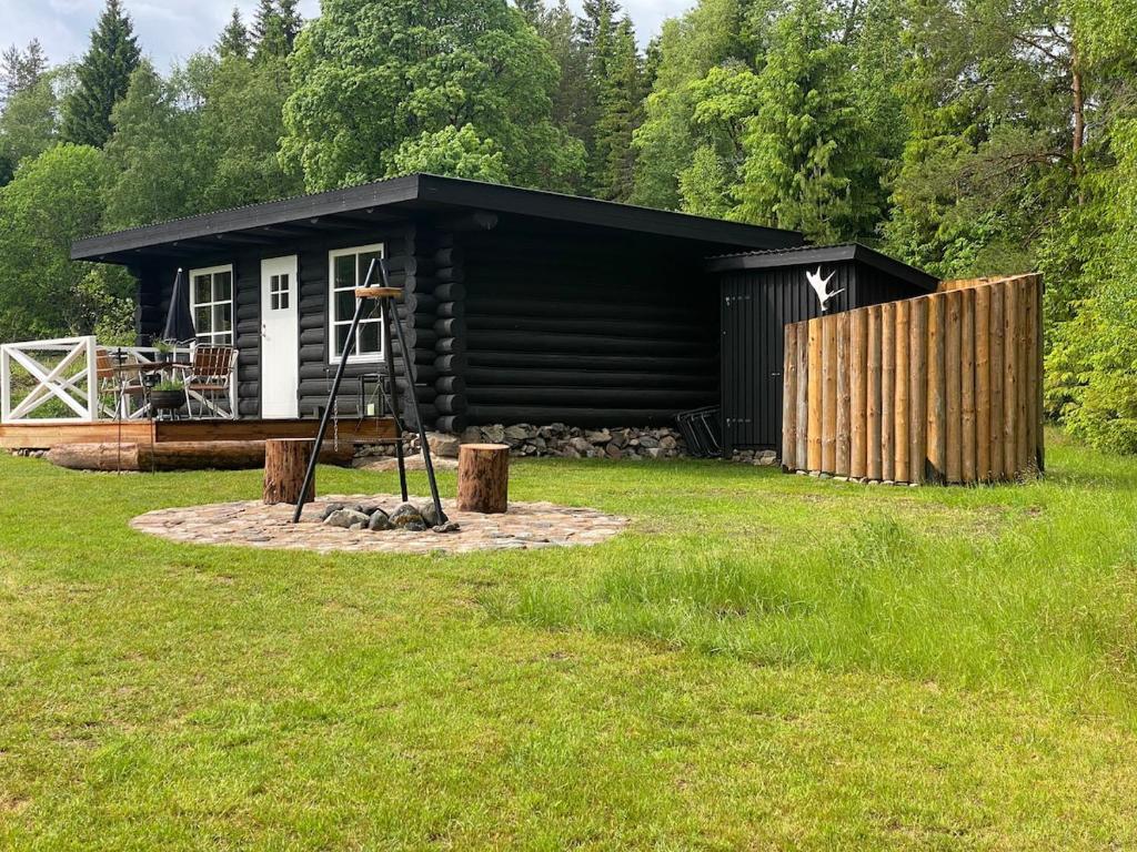 eine kleine schwarze Hütte auf einem Grasfeld in der Unterkunft Vildstugan in Björksjön