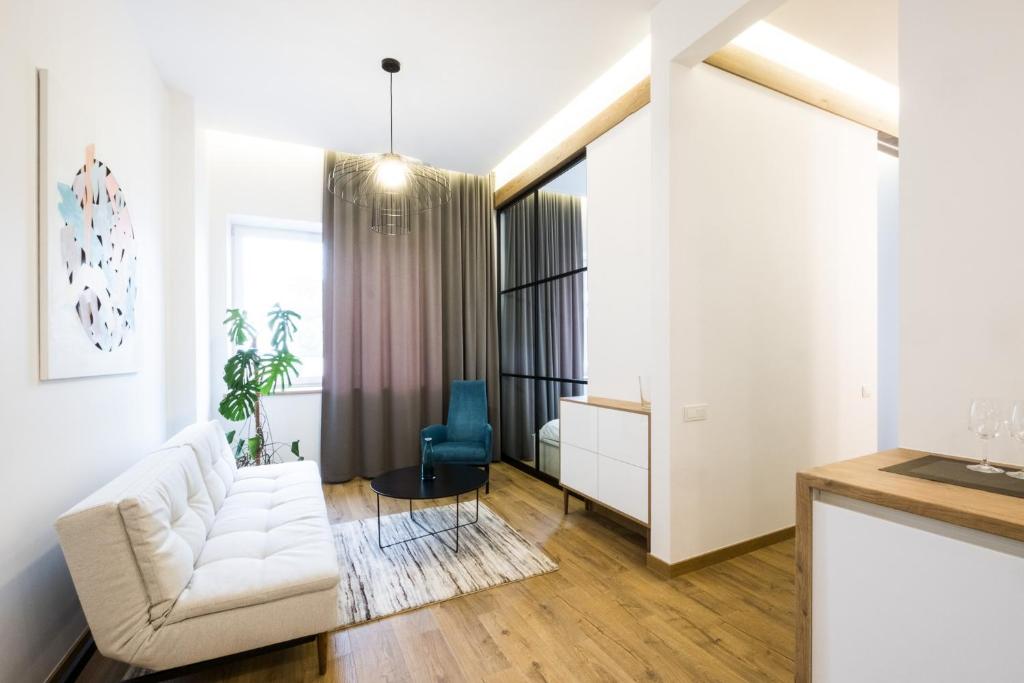 ein Wohnzimmer mit einer weißen Couch und einem blauen Stuhl in der Unterkunft Apartment on Dauksos 18 in Kaunas