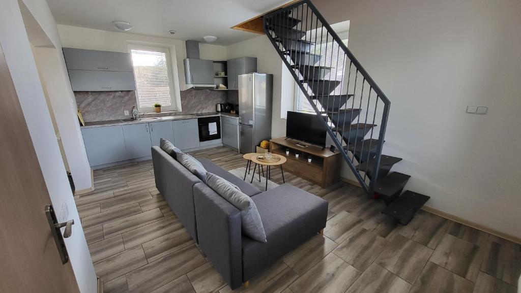 a living room with a couch and a spiral staircase at Apartmán u kolejí A in Kašnice