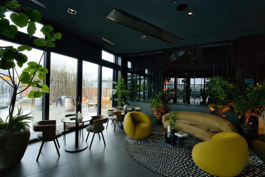 a lobby with a couch and chairs and tables and windows at Hotel ROMY by AMANO in Berlin