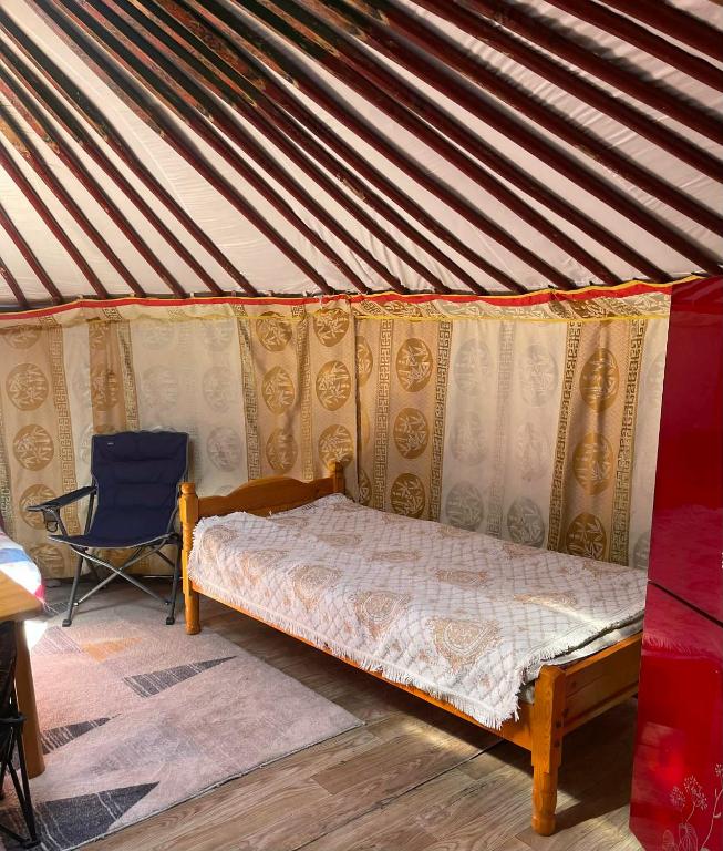 a bedroom with a bed and a chair in a tent at Yurt near terelj in Nalayh