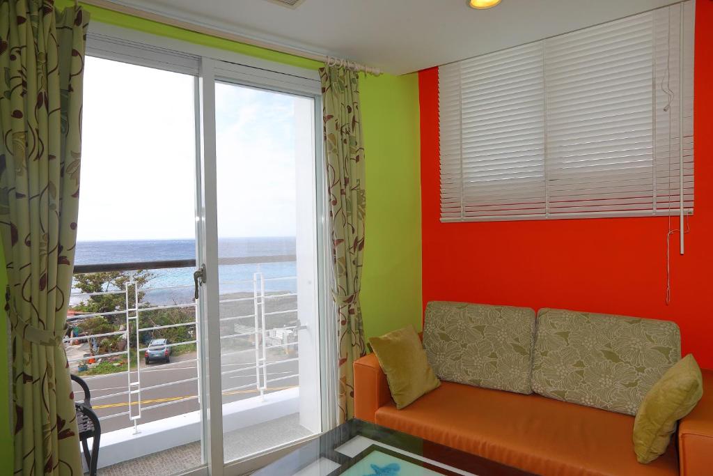 a living room with a couch and a large window at Hang Hai B&amp;B in Eluan