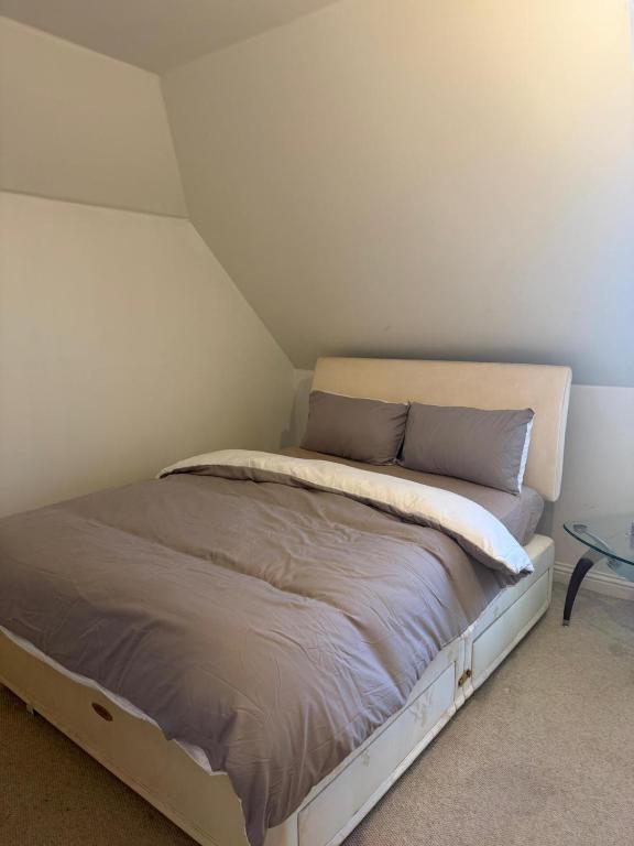 a bed in a room with a white wall at Cosy House in Reading
