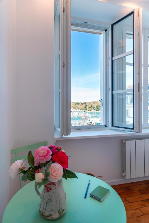 a vase of flowers sitting on a table with a window at Lumineux logement vue sur le port in Audierne