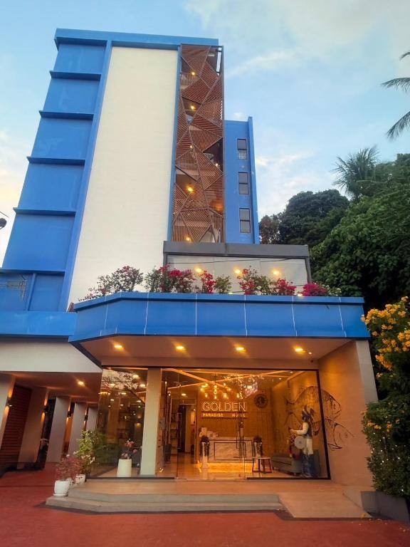 a blue and white building with people in it at Golden Paradise Hotel - SHA PLUS in Karon Beach
