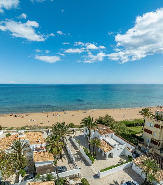 a view of a beach with palm trees and the ocean at Urbanización El Oasis, 20 Villas en 1ª Línea Playa in Denia
