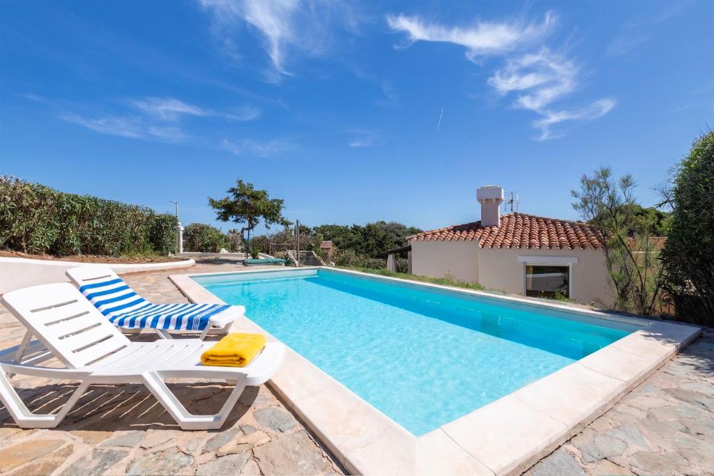 a swimming pool with two lounge chairs and a house at Villa Sabbia - Private pool in Stintino