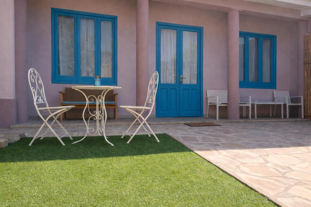a patio with chairs and a table and blue doors at Domos Ventuno Barumini in Barùmini