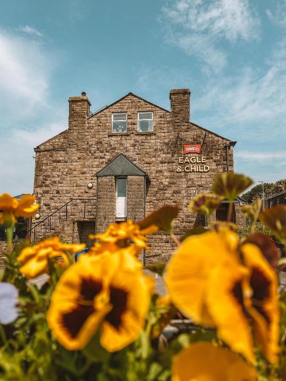 a brick building with yellow flowers in front of it at Eagle and Child, Ramsbottom in Bury