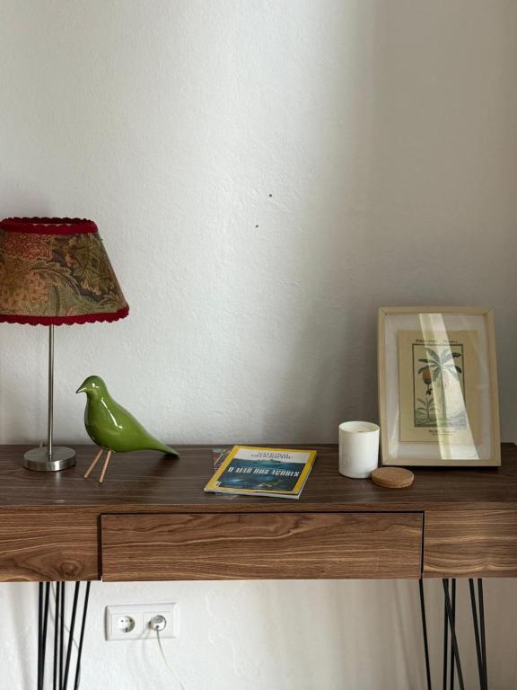 a table with a lamp and a book and a bird on it at Casa & Caminho AL in Velas