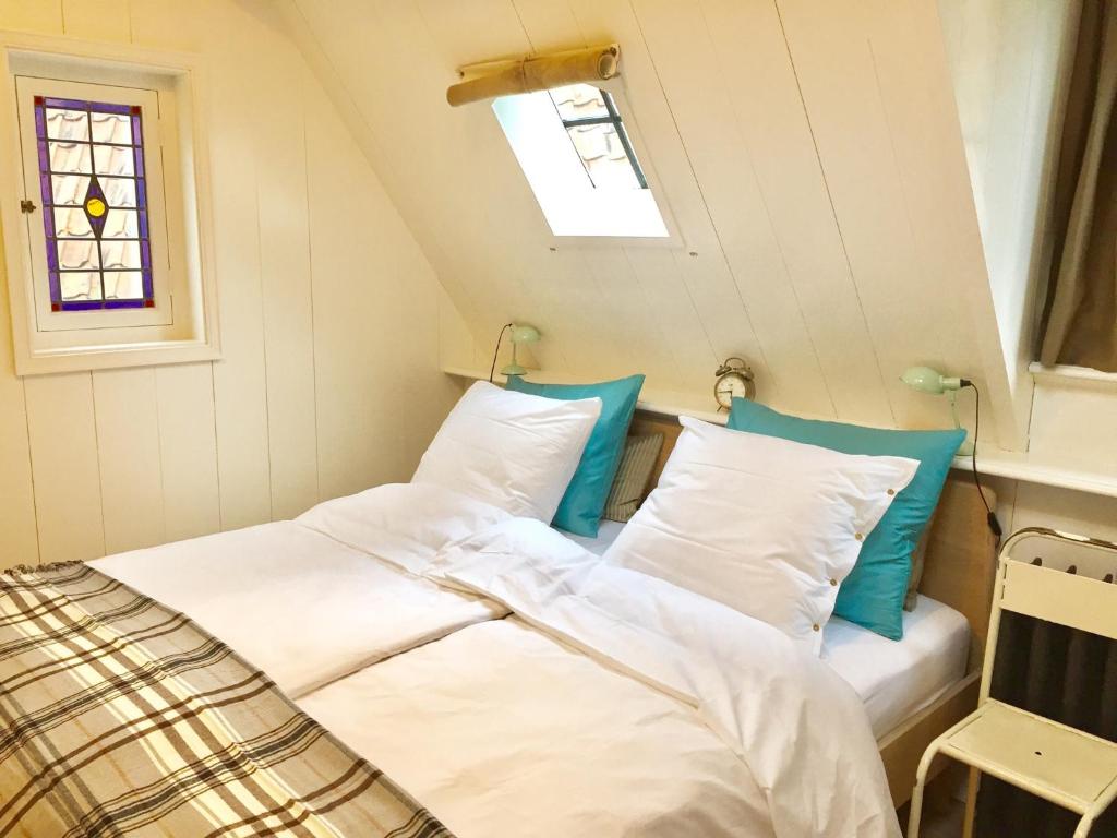 uma cama com lençóis brancos e almofadas azuis num quarto em Klein Loenen em Loenen aan de Vecht
