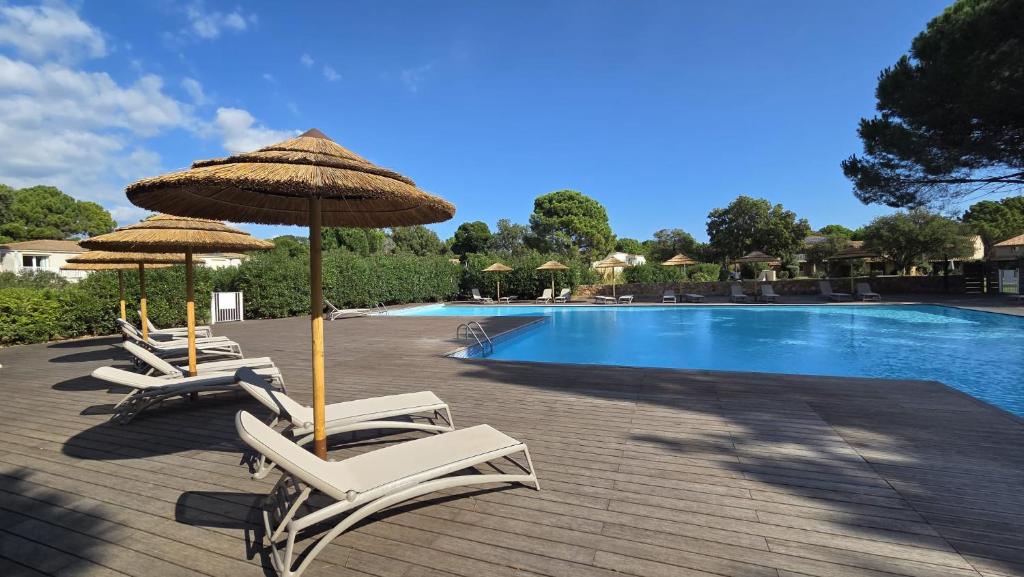 a group of chairs and umbrellas next to a swimming pool at Maison/appartement proche Cala Rossa in Lecci