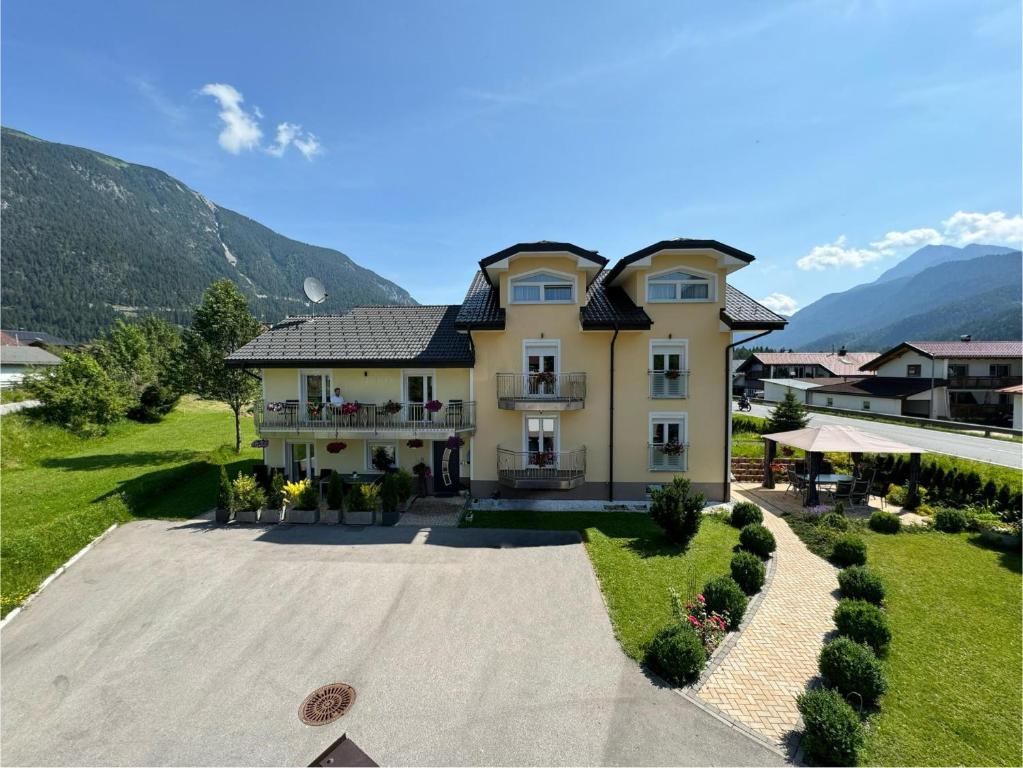 an aerial view of a house with mountains in the background at Ferienwohnung Schönblick in Weissenbach am Lech