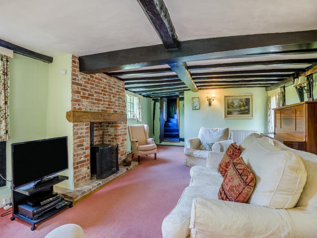 a living room with white furniture and a fireplace at Glebe Cottage in Powick