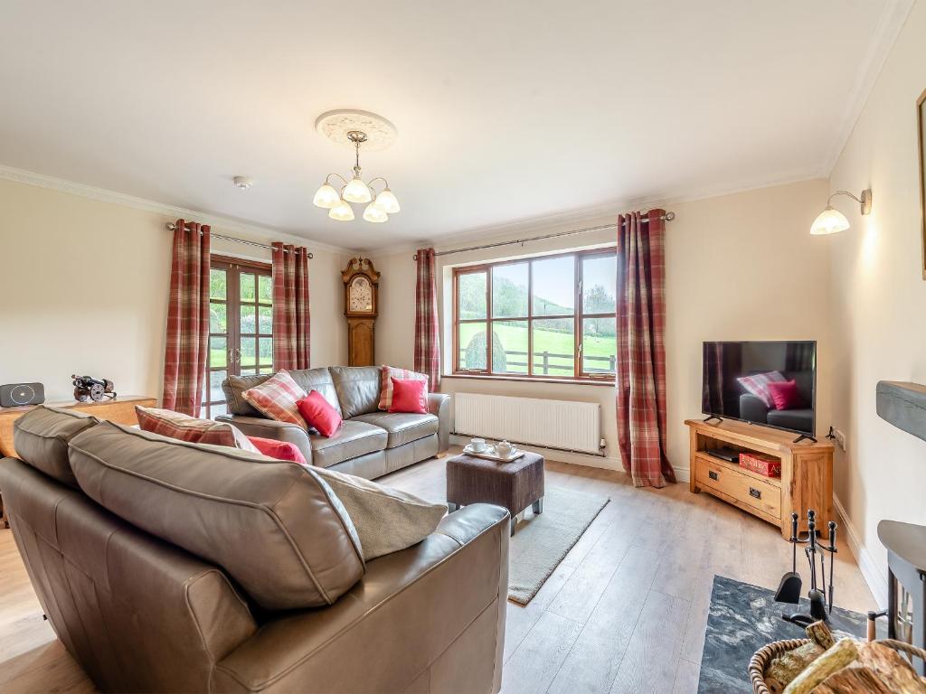 a living room with a couch and a tv at Melancroft in Llanfihangel-nant-Melan