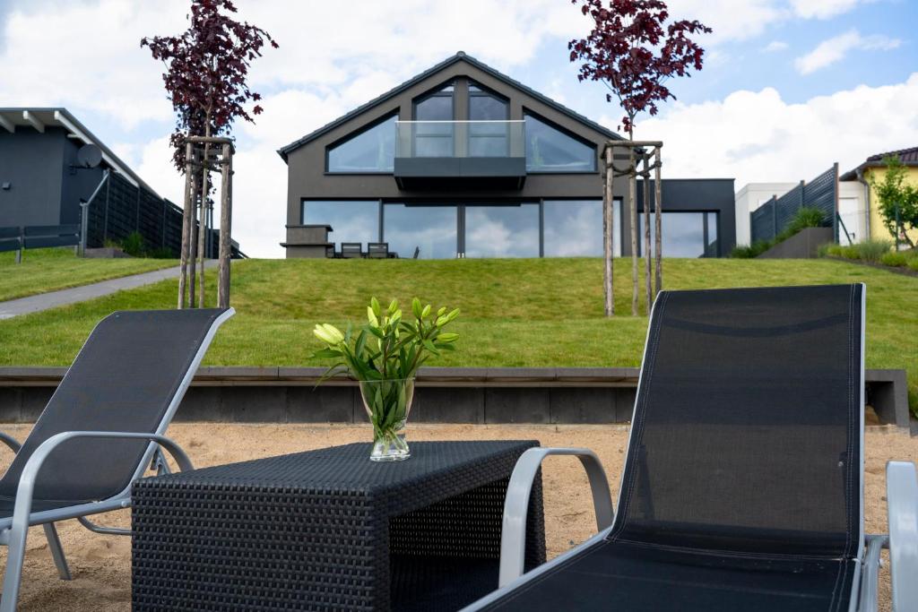 a table with two chairs and a house at Ferienhaus SUNSHINE am Mühlfeldsee in Löbnitz