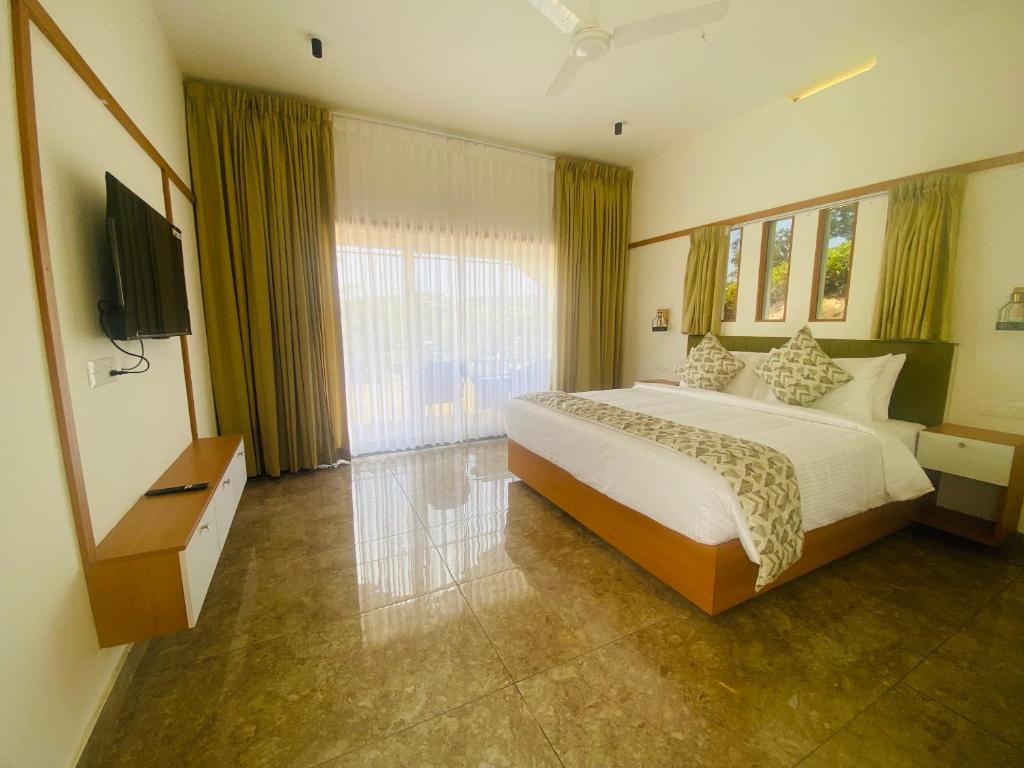 a bedroom with a large bed and a television at Misty Glen in Vagamon