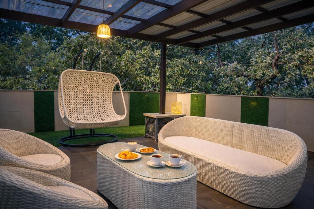 a patio with wicker chairs and a table with food on it at Hotel LA Eden in Mussoorie