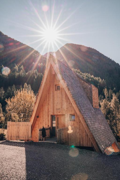 a wooden barn with the sun in the sky at Collis Hill Chalets & Hotel in Kals am Großglockner