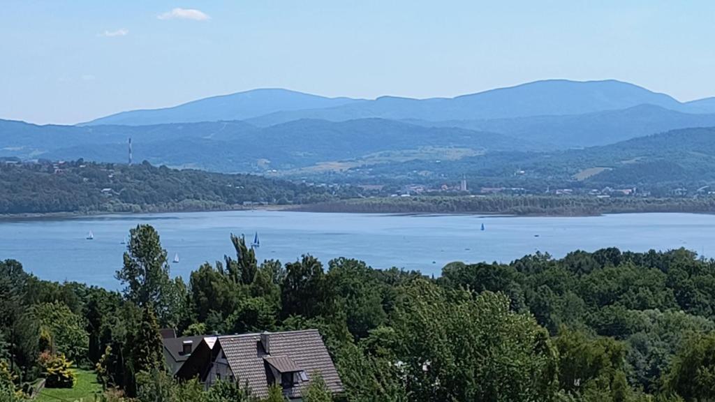 a view of a lake with a house in the foreground at Domki Mała Tresna in Bierna