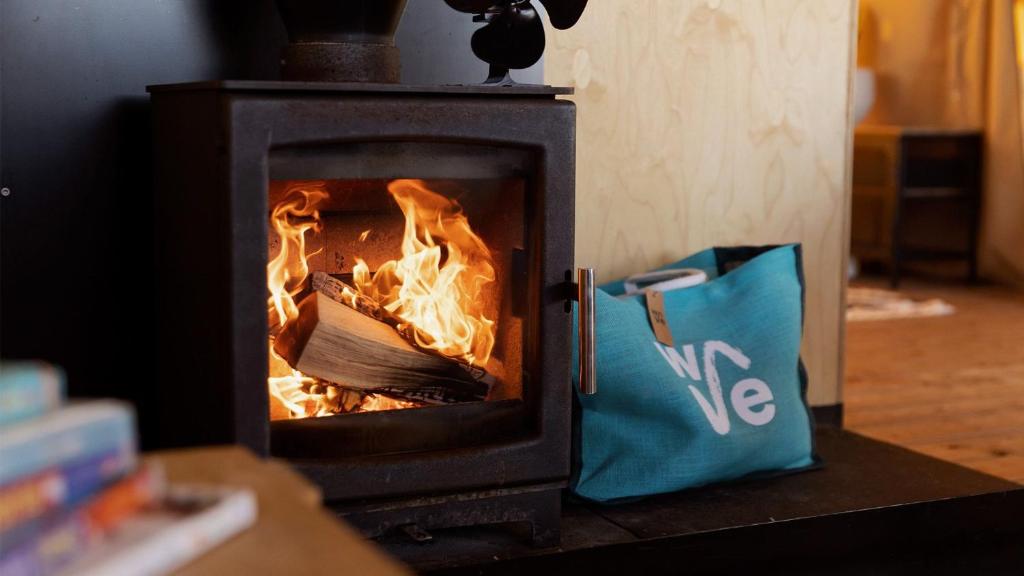 a wood stove with fire in it next to a bag at The Camp at The Wave in Bristol
