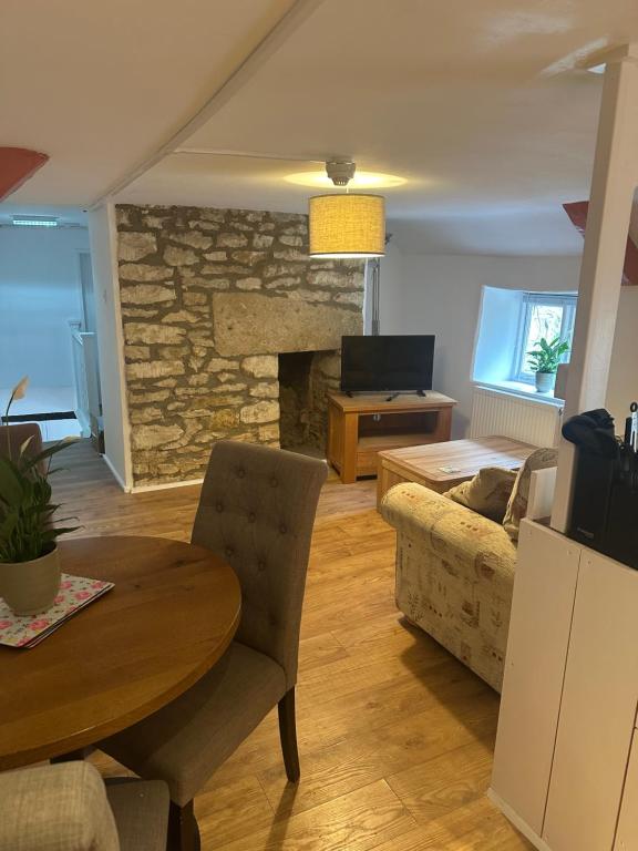 a living room with a table and a fireplace at The Hayloft in Oaksey
