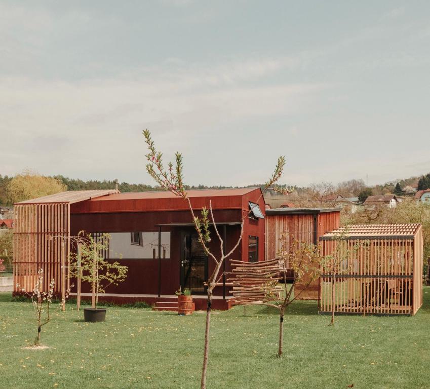 a red house with a fence in a yard at Rusty Cabin -Tiny House in Neustift an der Lafnitz