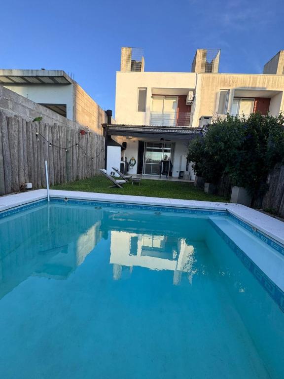 a swimming pool in front of a house at Beautiful fully-equipped duplex in Ezeiza