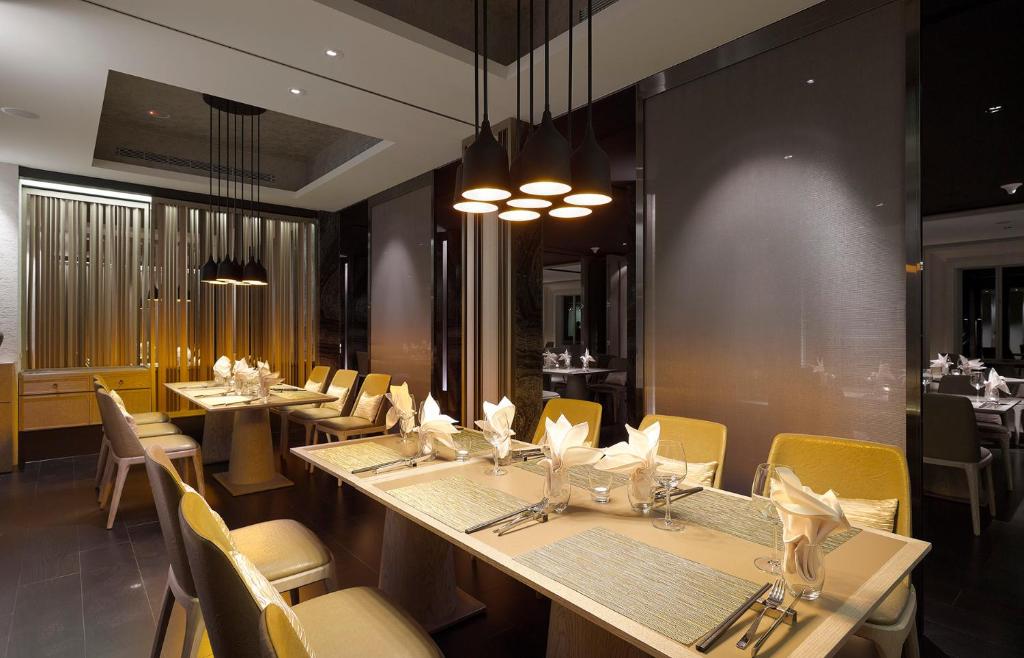 a dining room with long tables and yellow chairs at Gloria Manor in Kenting