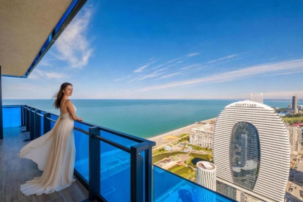 a woman standing on a balcony with a view of the ocean at Orbi HighView Panoram Hotel in Batumi
