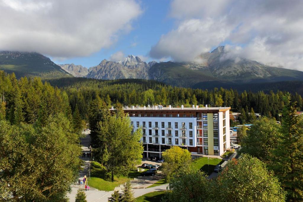 a large building with mountains in the background at Hotel CROCUS in Štrbské Pleso