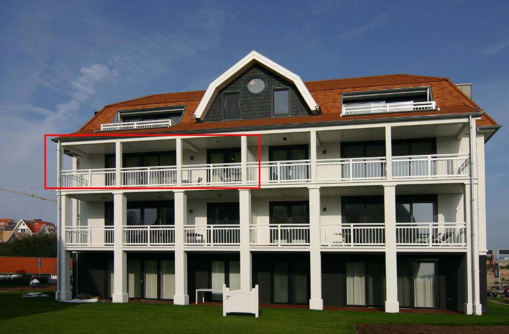 a large white building with a red roof at Duinhof IX E204 in Cadzand