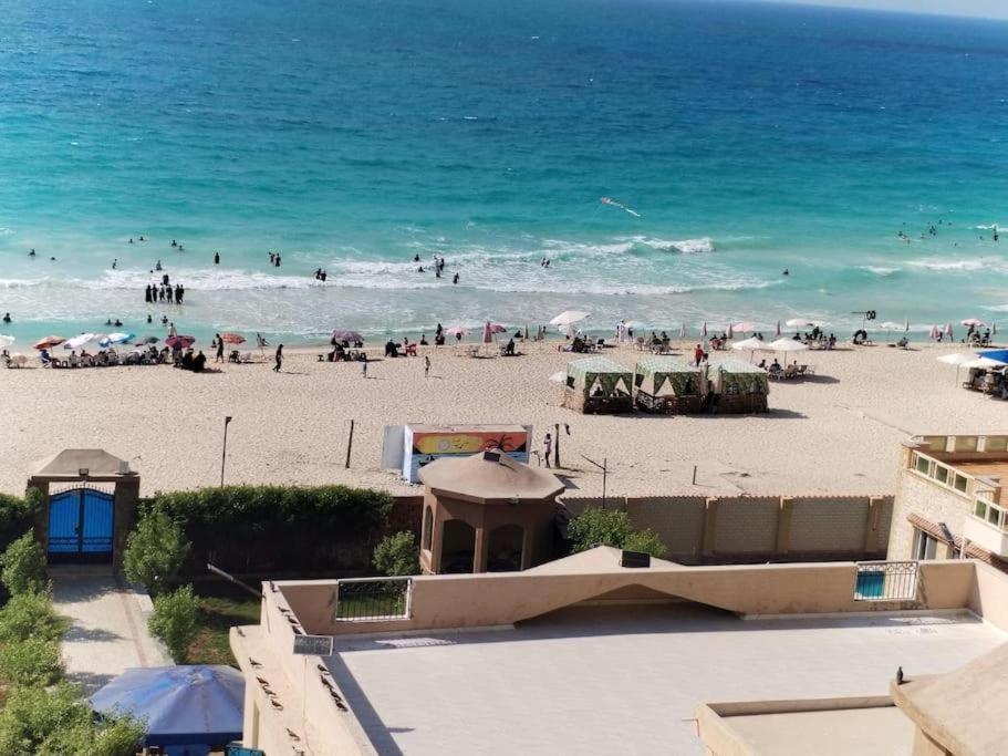a beach with a crowd of people in the water at شقة على البحر- Seafront Apartment in El Delr