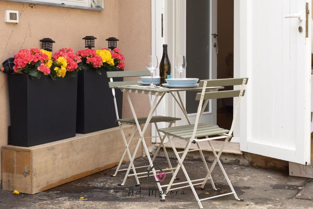 a table and chairs on a porch with flowers at Il Gioiello di Frieda - in centro a Muggia in Muggia
