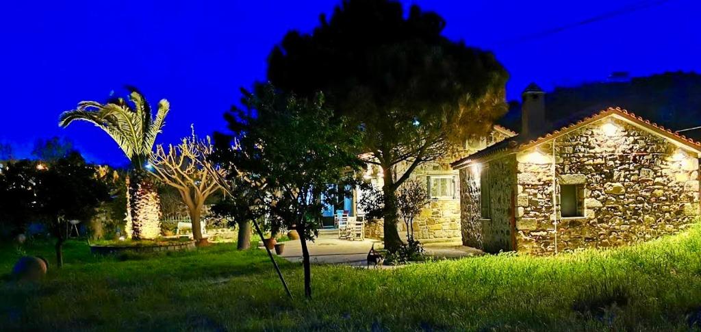 a stone house with lights in a yard at night at Agroktima Konstantinos & Eleni in Platy