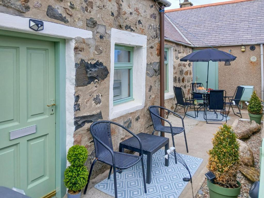 a patio with chairs and an umbrella next to a building at Puffin Cottage in Fraserburgh