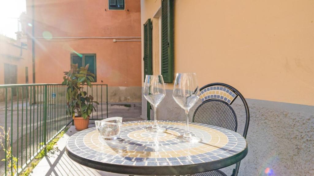 a table with two wine glasses on a balcony at Suite Alarcon - Goelba in Porto Azzurro