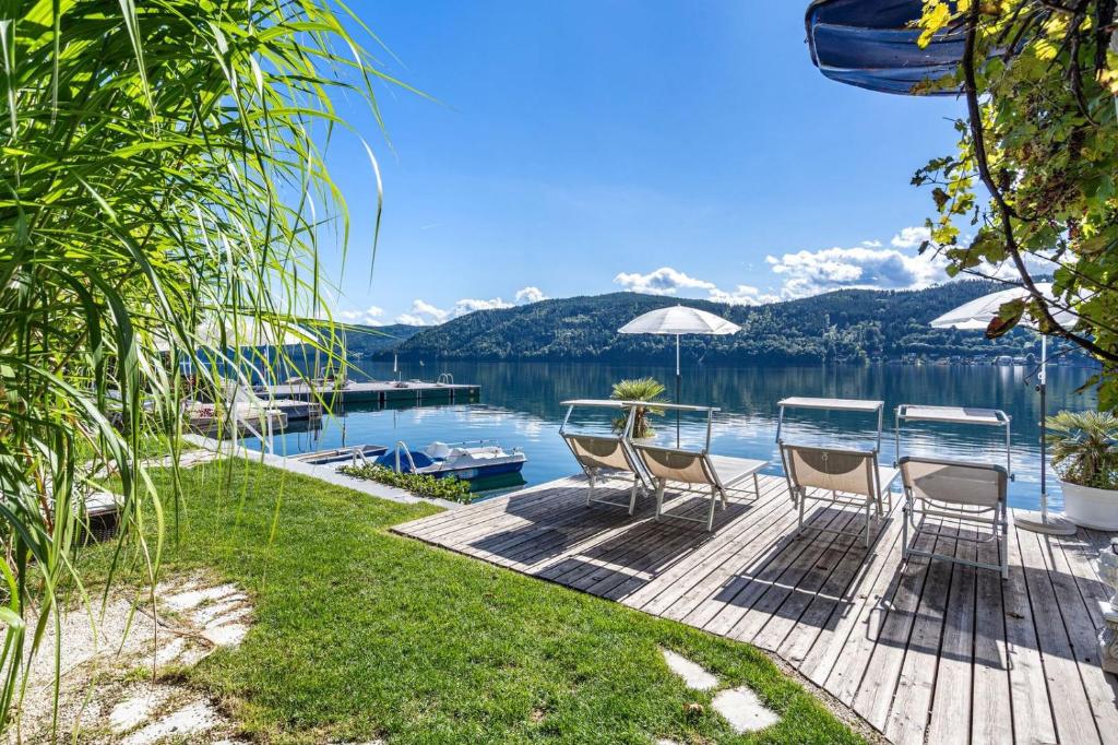 a patio with chairs and a table with a view of a lake at Hotel Nikolasch mit eigenem Seebad - Adults Preferred in Millstatt