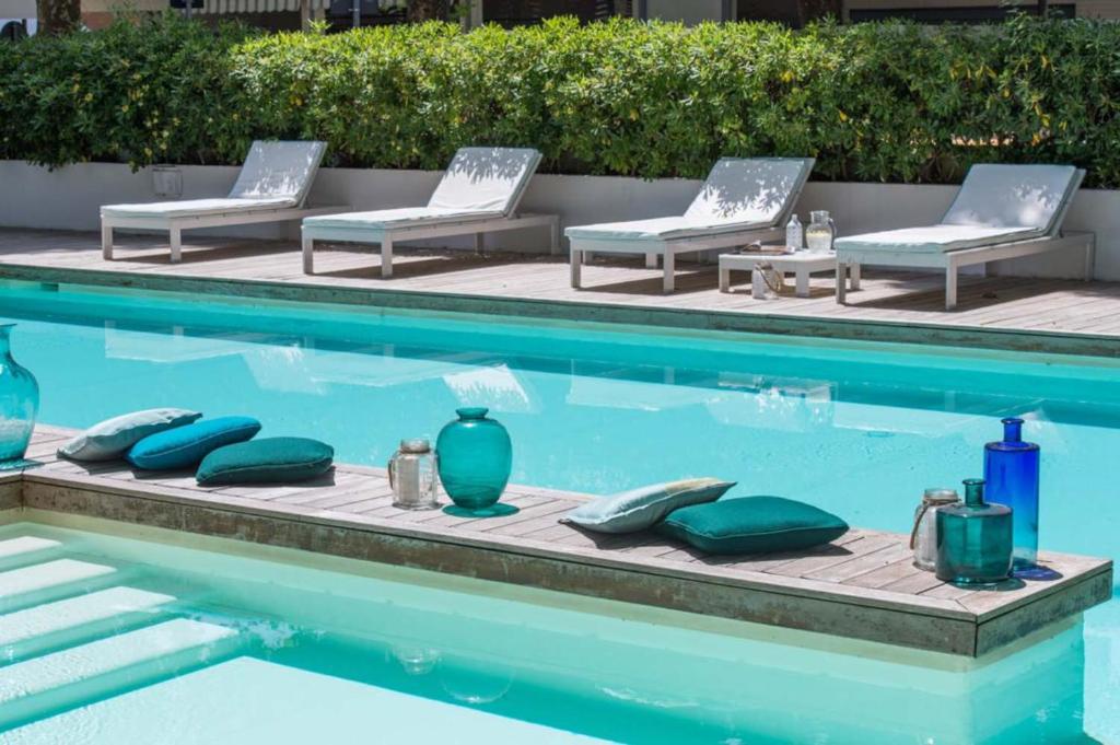 a swimming pool with chaise lounge chairs and vases at Hotel Prestigio in Milano Marittima
